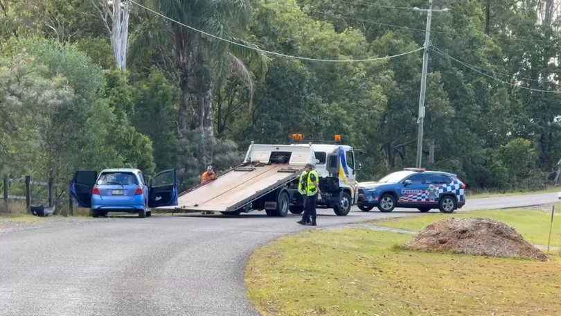 A tow truck prepares to remove the crashed blue hatchback with the road closed for hours.