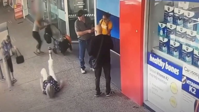 The elderly woman falls to the ground after being struck by a pram in the middle of the footpath.