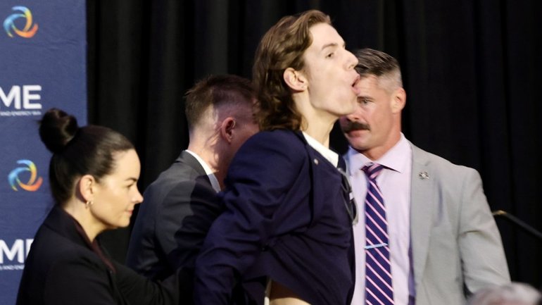 A protester is led from CME breakfast with the PM this morning at The Westin Hotel in Perth.