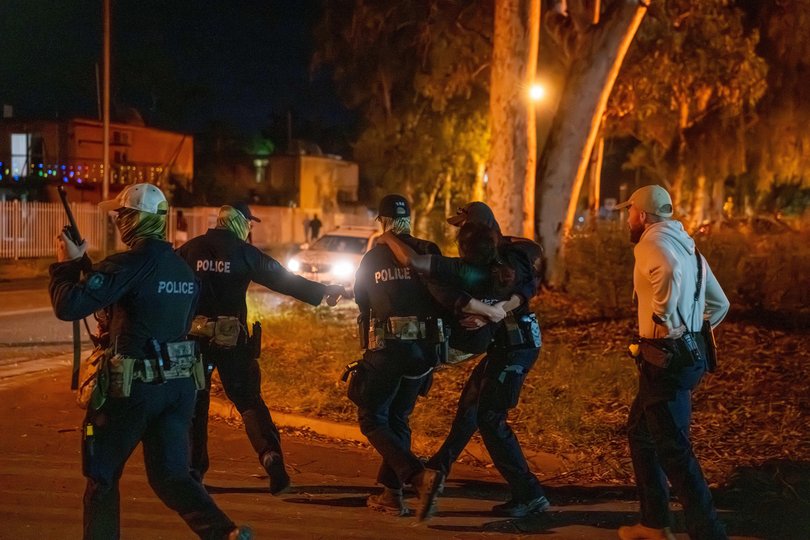 A woman is carried by police during community unrest outside Alice Springs Hospital.