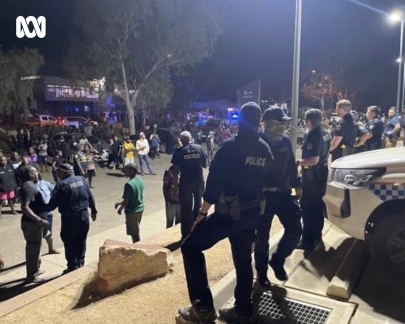 A full-scale riot has broken out in front of Alice Springs Hospital, with police pelted with rocks and a police car set alight.