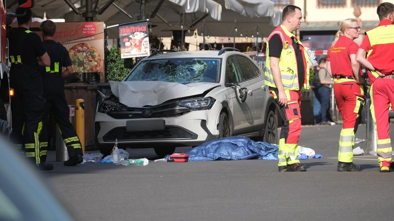 Rescue workers stand next to a damaged car that crashed into several people in Leipzig. 