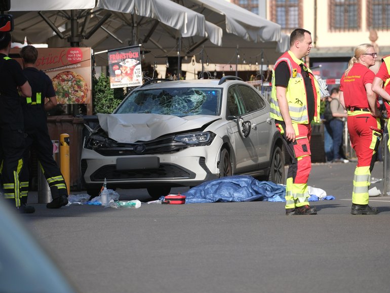 Rescue workers stand next to a damaged car that crashed into several people in Leipzig. 
