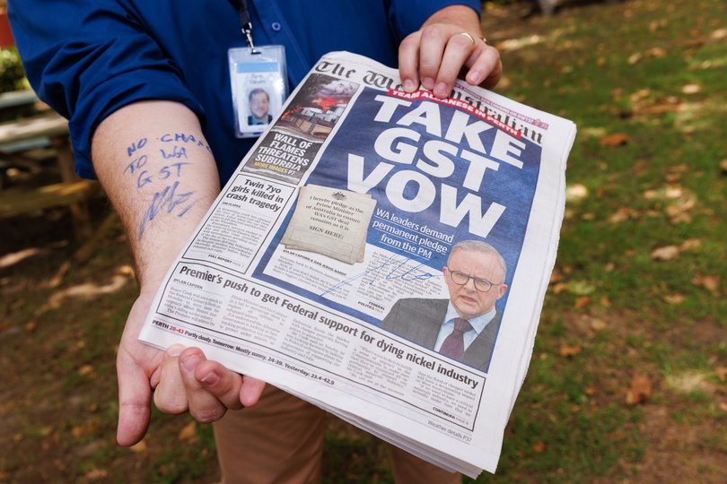 Dylan Caporn, State Political reporter for The West Australian shows his arm and a newspaper after Prime Minister Anthony Albanese wrote and signed No Change To WA GST. 