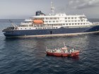 An ambulance boat carrying crew members wearing hazmat suits approaches the hantavirus stricken cruise ship MV Hondius, while stationary off the port of Praia, in Cape Verde.