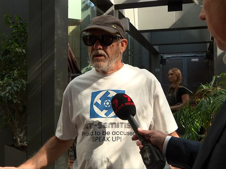 Ian Minus outside the Bondi Royal Commission in Sydney wearing a swastika shirt.