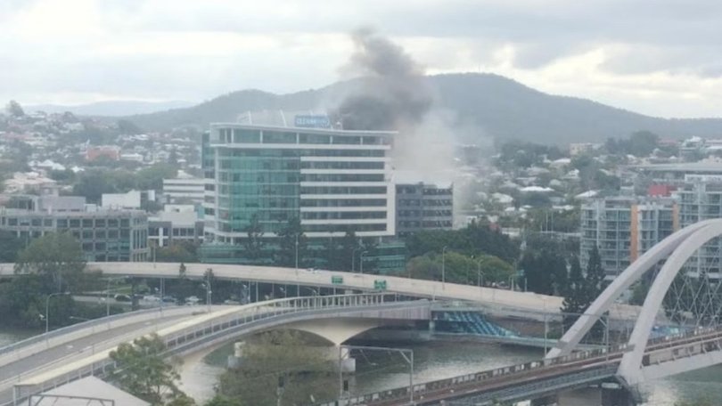 A dramatic rooftop rescue is underway in inner-city Brisbane after a fire broke out on the top level of a multistorey building, leaving a person stranded above the blaze.