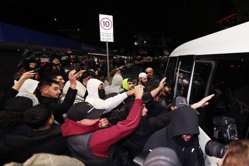 MELBOURNE, AUSTRALIA - MAY 07: A group of supporters shield recently arrived people with links to Islamic State as they move into a bus outside Melbourne Airport on May 07, 2026 in Melbourne, Australia. The women, who had traveled to Syria to join the Islamic State militant group, are expected to face questioning by Australian Federal Police upon their arrival, with authorities weighing potential charges under counter-terrorism legislation. (Photo by Morgan Hancock/Getty Images)