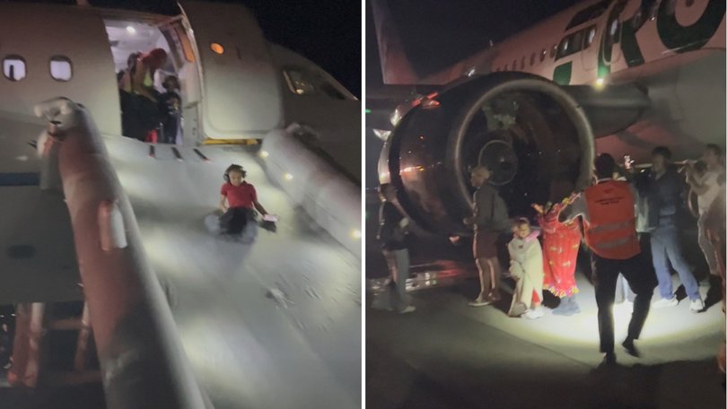 Passengers are evacuated off the plane then pause to take phtotos of the engine where the pedestrian died.