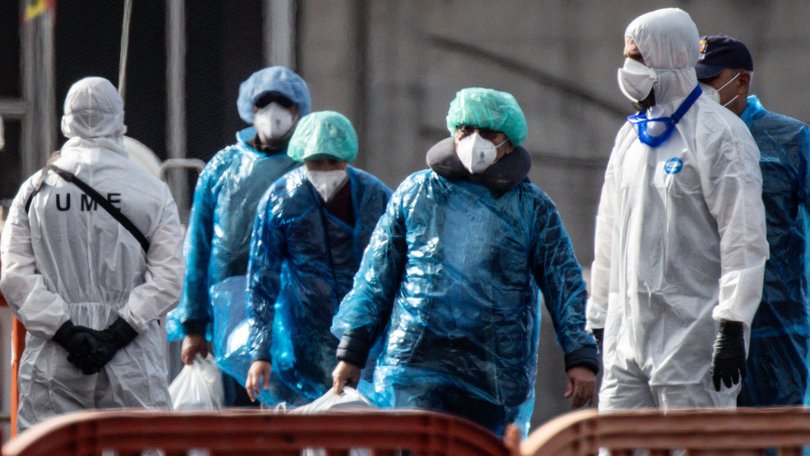 Passengers carry their belongings in plastic bags after being evacuated from the MV Hondius.