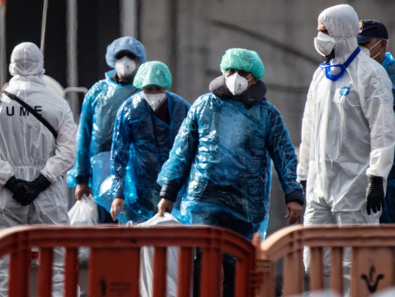 Passengers carry their belongings in plastic bags after being evacuated from the MV Hondius.