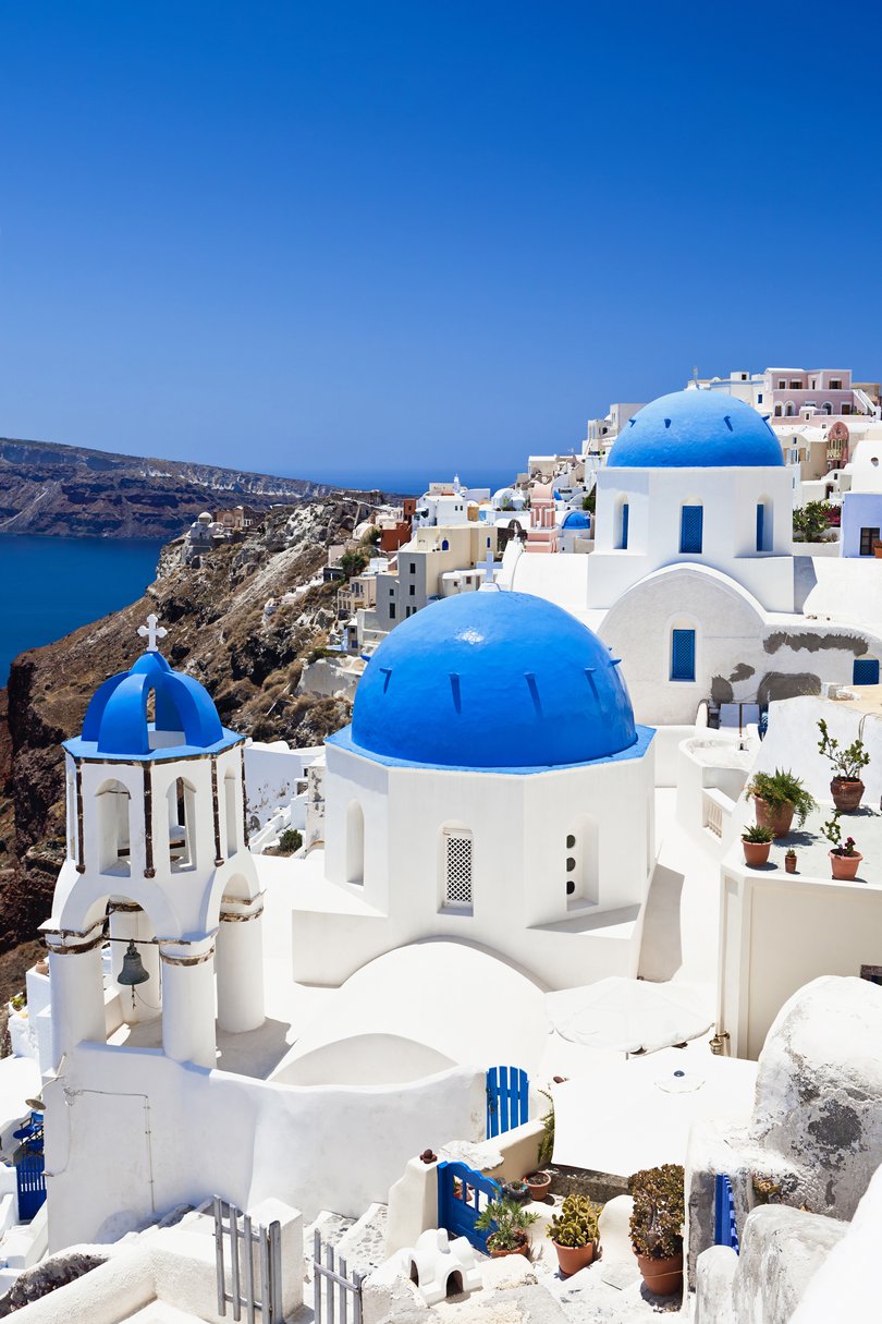 Famous Orthodox church with blue domes in village Oia (Ia) on Santorini island. 