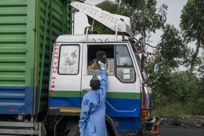 A health worker, deployed in response to an Ebola outbreak, takes the temperature of a truck driver passing through the Kanyaruchinya checkpoint at the northern entrance of Goma, Democratic Republic of Congo.