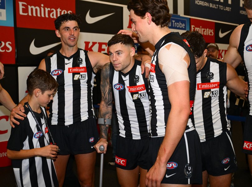 Jamie Elliott of the Magpies is consoled by teammates.