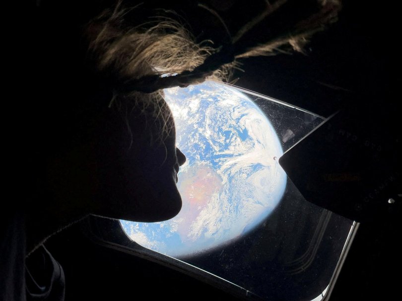 A photo provided by the NASA shows Artemis II mission specialist Christina Koch peering out one of the Orion spacecraft's main cabin windows.