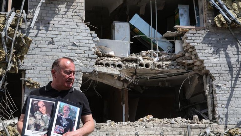 A teacher with the portraits of students who died when the dormitory came under attack. 