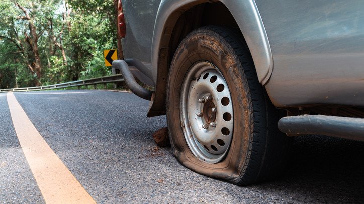 Two men have been charged after police alleged a woman was threatened with a knife and dragged toward an SUV while changing a flat tyre.