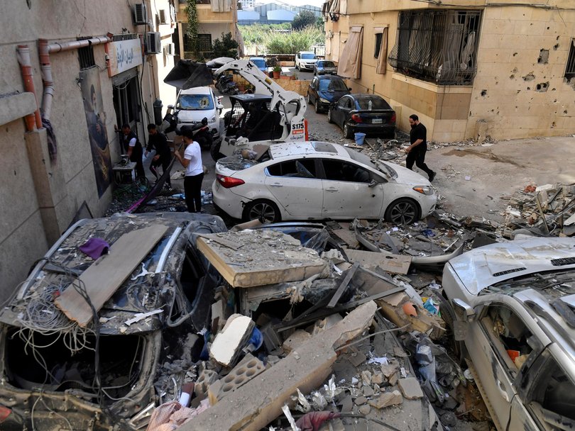 Members of Hezbollah gather near damaged vehicles following an Israeli airstrike south of Beirut.