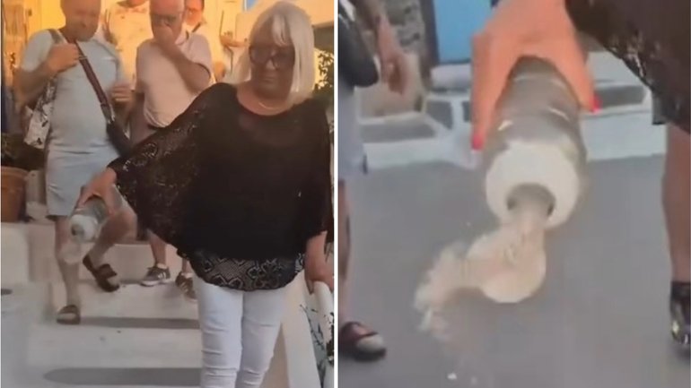 The woman empties what appears to be ashes onthe streets of Oia in Santorini