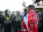 A man draped in a Union Flag stands in front of riot police as protesters gather near the location where Henry Nowak died.