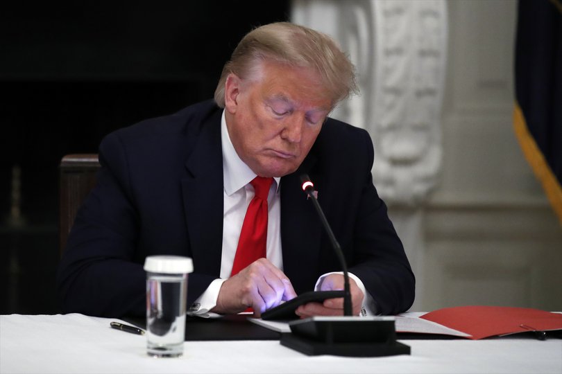 President Donald Trump looks at his phone during a roundtable with governors on the reopening of America's small businesses during his first term in the White House on June 18, 2020.