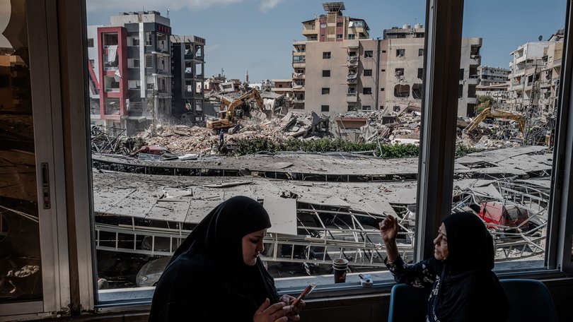 Women smoke as they look through damaged windows at Jabal Amel Hospital near the site of an Israeli strike Monday in the southern port city of Tyre, Lebanon.