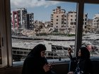 Women smoke as they look through damaged windows at Jabal Amel Hospital near the site of an Israeli strike Monday in the southern port city of Tyre, Lebanon.