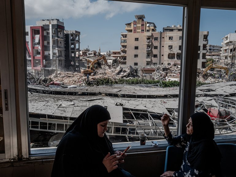 Women smoke as they look through damaged windows at Jabal Amel Hospital near the site of an Israeli strike Monday in the southern port city of Tyre, Lebanon.