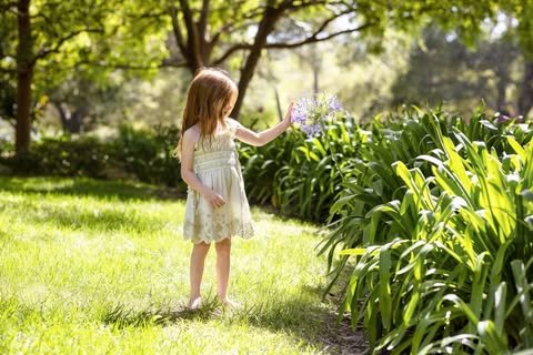 In a second image posted to social media on Meghan Markle's account, Lilibet can be seen holding a flower in a garden.