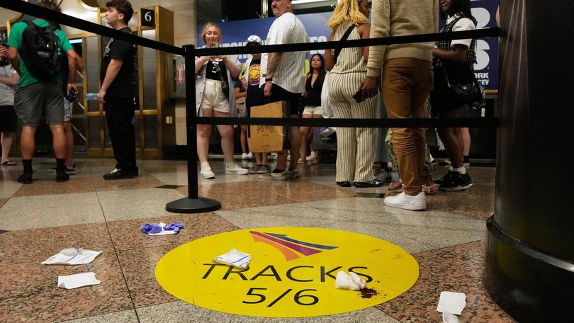 People stand near an area roped off after a stabbing at Penn Station.