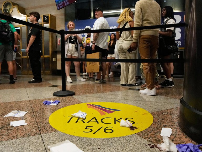 People stand near an area roped off after a stabbing at Penn Station.