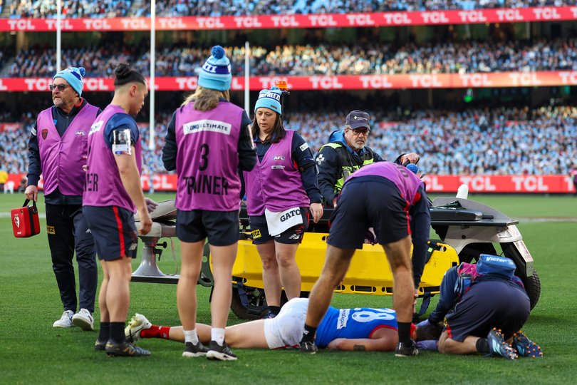 Brody Mihocek of the Demons is assisted by medical staff.