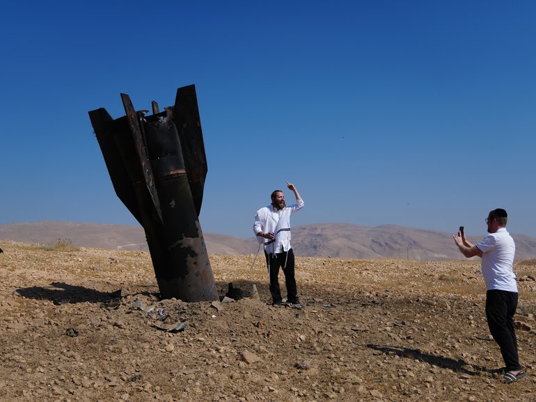 People take their photos beside the wreckage of an Iranian missile that landed near the West Bank city of Jericho Monday, June 8, 2026. (AP Photo/Mahmoud Illean)