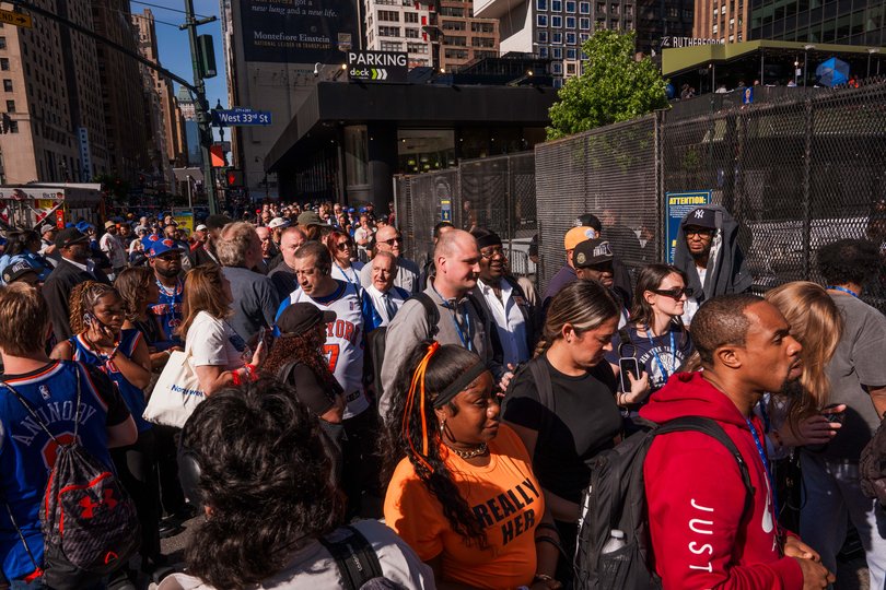 People line up along a security fence to enter Madison Square Garden.