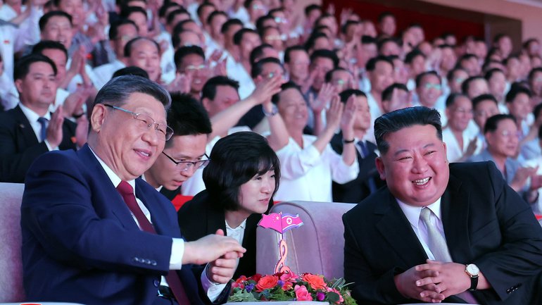  A photo released by the official North Korean Central News Agency (KCNA) shows Chinese President Xi Jinping (L) and North Korean leader Kim Jong Un chatting during an artistic performance to welcome the Chinese leader in Pyongyang