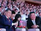  A photo released by the official North Korean Central News Agency (KCNA) shows Chinese President Xi Jinping (L) and North Korean leader Kim Jong Un chatting during an artistic performance to welcome the Chinese leader in Pyongyang