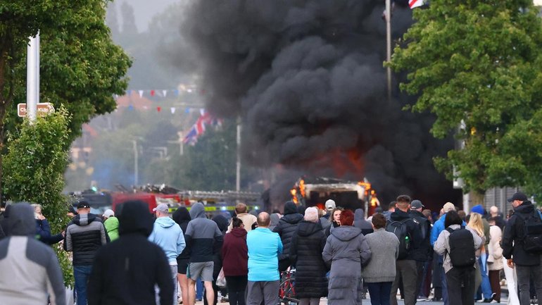 People watched on as a vehicle burned during a protest following a stabbing in Belfast. (AP PHOTO)