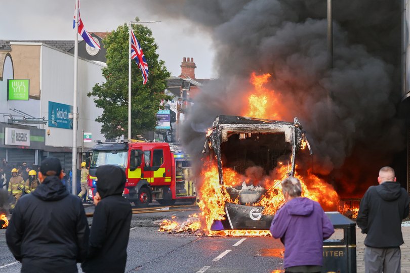 People watch as a vehicle burns during a protest in East Belfast following a stabbing incident in Belfast, Tuesday, June 9, 2026.