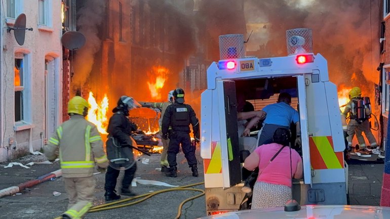 A family get into a  vehicle after being rescued from houses which caught fire in Lendrick Street in east Belfast, as disorder flared in response to Monday night's stabbing attack in the city. 