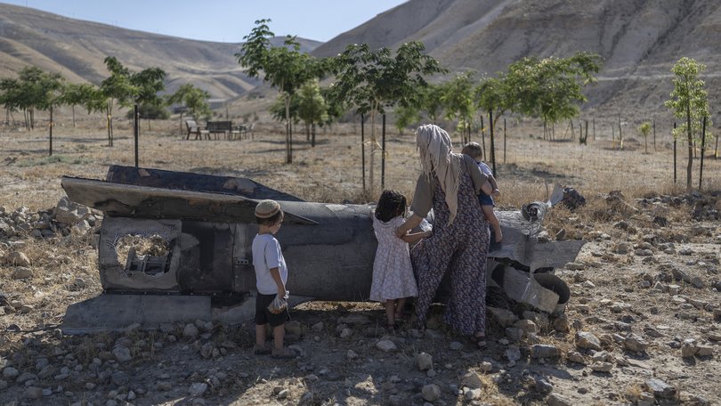 Israeli settlers look at a fallen rocket, outside a Jewish settler farm on the outskirts of Israeli-occupied West Bank city of Jericho.