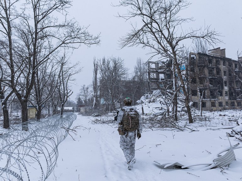 Oleg, a Ukrainian serviceman from the 24th Brigade, walks in front of a building damaged by Russian bombing in Kostiantynivka, Ukraine.