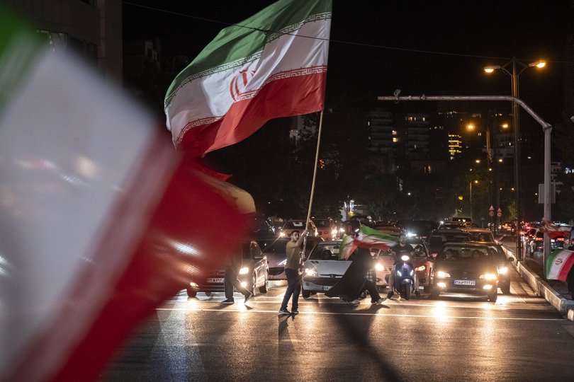 A pro-government supporter waves a giant Iranian national flag during a nightly rally in northern Tehran, Iran, on June 8, 2026.