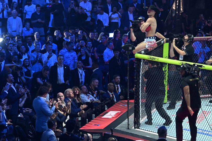 President Donald Trump sits between first lady Melania Trump and Dana White, the president and CEO of the Ultimate Fighting Championship, as he looks up at Diego Lopes after Lopes won his match.