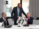 U.S. President Donald Trump, right, holds up a jersey with the number 47 on it as British Prime Minister Keir Starmer, left, and German Chancellor Friedrich Merz look on during a working session at the G7 summit.