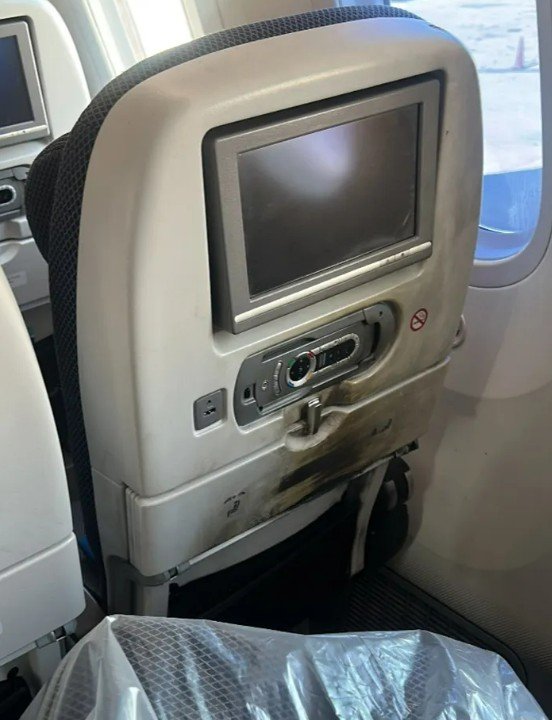 The back of the seat and tray table scarred with soot.