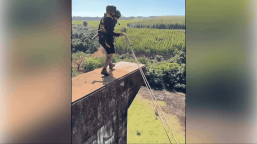 Holding a child, he jumps off a bridge attached only to a rope.