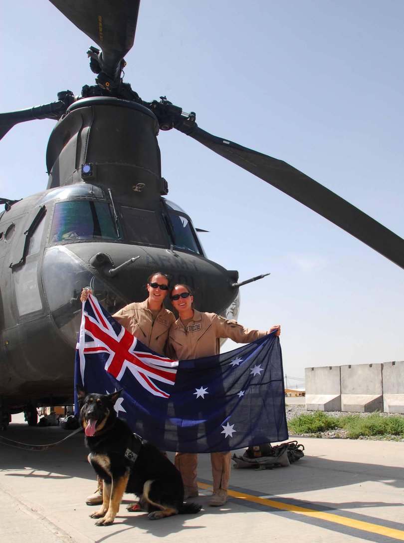 Chinook helicopter pilots, Captain Naomi Rogusz and Captain Sacheen Gallop, with Military Working Dog "Kim", display one of the Legacy Aussie flags which they are taking on their mission over Afghanistan.