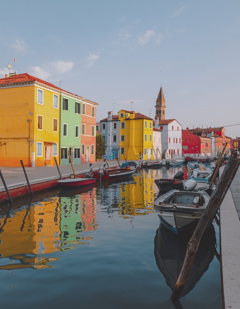 Colourful houses on the canal in famous travel destination Burano island and boats lining side canals with beautiful reflection in Burano, Venice, Italia