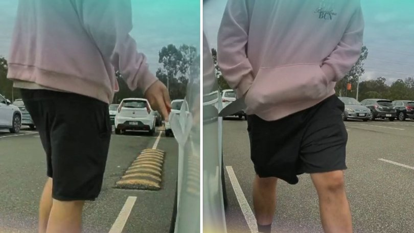 Security footage from the Eight Mile Plains park-and-ride shows a hooded man scanning the area before drawing a large knife and dragging the blade along the Tesla.
