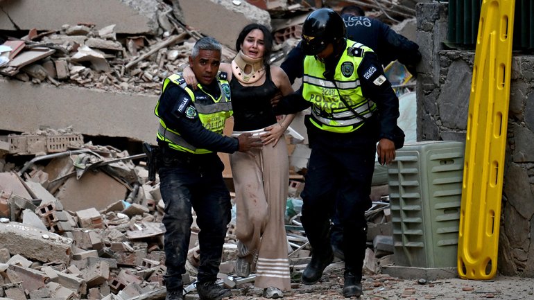Municipal police officers evacuate an injured victim from a collapsed building in Caracas.